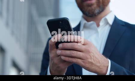 Nahaufnahme nicht erkennbarer reifer Geschäftsmann hält Handy in der Stadt unbekannter Geschäftsmann professioneller Manager, der Smartphoneservices durchblättert Stockfoto