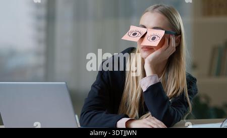 Erschöpfte, langweilige, verschlafene kaukasische Geschäftsfrau mit Haftnotizen auf den Augen Brille, die vorgibt, im Büro aufzuwachen, müde Geschäftsfrau weiblich Stockfoto