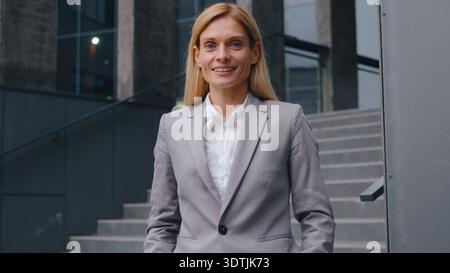 Zufriedene, glückliche, kaukasische Geschäftsfrau in der Stadt lächelnd in die Kamera schauend positiv, fröhlich, glückliche Geschäftsfrau mittleren Alters, weibliche Arbeitgeberin Stockfoto