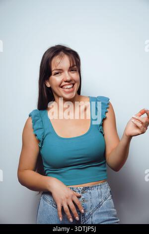 Fröhliche junge Frau lächelt isoliert auf neutralem Studio-Hintergrund. Stockfoto