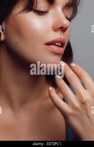 Nahporträt einer expressiven jungen Frau, isoliert auf neutralem Hintergrund. Stockfoto