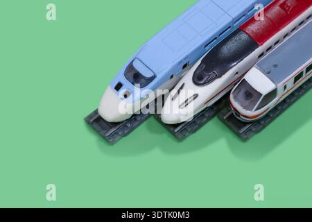 Drei Miniatur-shinkansen-Hochgeschwindigkeitszüge stehen auf Spielzeugbahngleisen mit Kopierraum. Stockfoto
