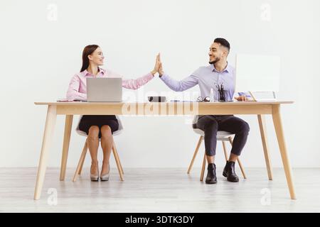 Teammitglieder teilen sich einen Moment an ihrem Schreibtisch während einer Arbeitssitzung in einer Büroumgebung Stockfoto