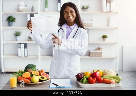 Diätassistent zeigt gesunde Lebensmittel Optionen und Ernährungsführer in einer hellen Küche Setting Stockfoto