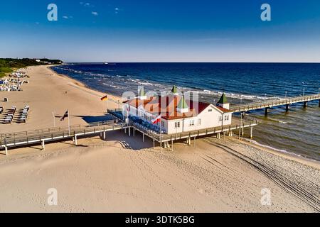 Ein idyllischer Blick aus der Luft fängt die historische Seebrücke in Ahlbeck auf der Insel Usedom ein, die in hellem Sonnenschein getaucht ist. Das elegante weiß Stockfoto