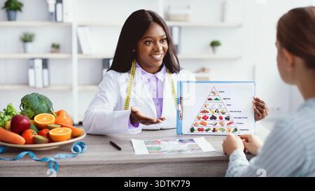 Ernährungswissenschaftler erklärt die Lebensmittelpyramide bei einer Beratung in einem Wellnesscenter Stockfoto