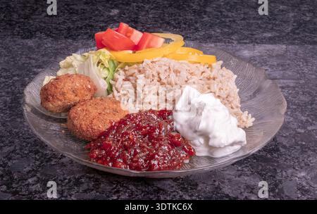 Ein nahrhafter vegetarischer Teller mit Falafel, Vollkornreis und frischem Gemüse, der für kommerzielle Zwecke gestaltet wurde. Stockfoto
