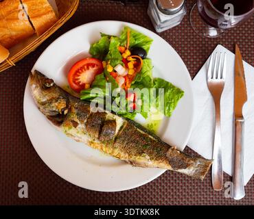 Leckeres Fischgericht, gegrillter Bass mit Gemüse und grüner Sauce Stockfoto