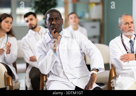 Afrikanischer Mann Doktor Student bei Kurstreffen hört dem Lehrer zu und schaut sich den Sprecher an Stockfoto