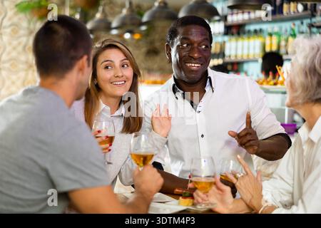 Glückliche Männer und Frauen, Freunde, genießen und lustige Feiertagsparty mit Gläsern Bier. Konzentrieren Sie sich auf afroamerikanische Männer Stockfoto
