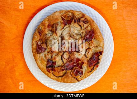 Ein horizontales Foto zeigt eine frische italienische Focaccia mit dünn geschnittenen roten Zwiebeln und herzhaftem Schinken auf weißem Teller Stockfoto