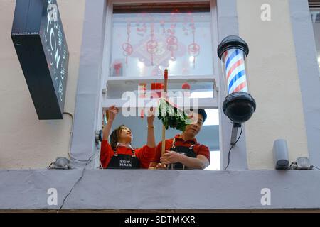 Die Mitarbeiter hängen einen Salat und lai See (rote Umschläge mit Geld) vor den Besuchen von Löwentänzern während der Mondneujahrsfeier in London. Stockfoto