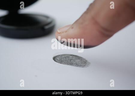 Fingerabdruck wird auf weißem Papier mit Tintenpad aufgenommen Stockfoto