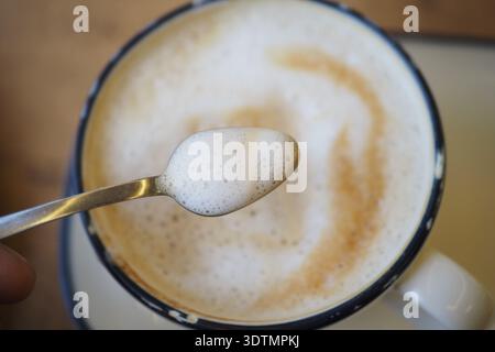 Löffel Rührschaum in einer Tasse Kaffee morgens Stockfoto