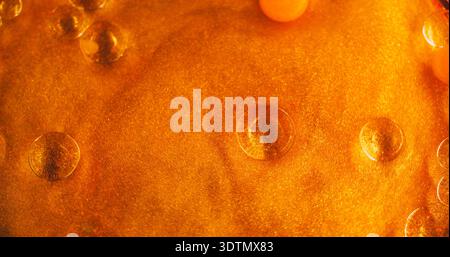 Farbblasen. Orangefarbene Ölflüssigkeit. Defokussierter heller Farbschimmer rund Wassertröpfchen Glitzerstruktur glänzende Flüssigkeit schwimmend auf abstraktem Kunsthintergrund. Stockfoto