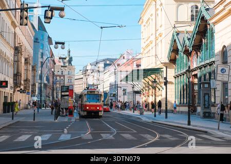 PRAG, TSCHECHISCHE REPUBLIK - 12. AUGUST 2024: Eine traditionelle rote Straßenbahnlinie 26 fährt entlang einer historischen Straße, die von klassischen Gebäuden in der Mitte gesäumt ist Stockfoto