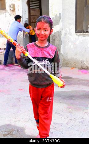 Hansi, Haryana, 14. März 20225: Unbekanntes indisches Kind mit einem Gesicht bedeckt mit rotem Pulver und einer Wasserpistole während des Holi Festivals Celebrati Stockfoto