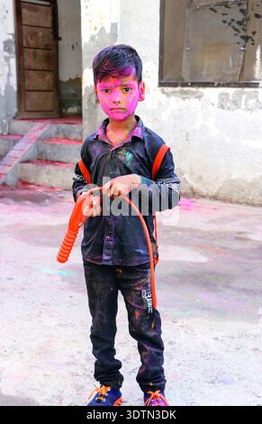 Hansi, Haryana, 14. März 20225: Unbekanntes indisches Kind mit einem Gesicht bedeckt mit rotem Pulver und einer Wasserpistole während des Holi Festivals Celebrati Stockfoto