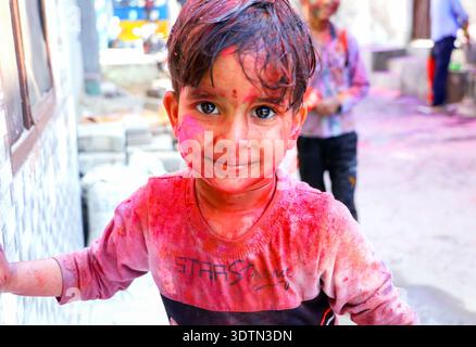 Hansi, Haryana, 14. März 20225: Nicht identifiziertes indisches Kleinkind mit Gesicht bedeckt mit rotem Pulver während der Holi-Festivalfeier in einem Bewohner Stockfoto