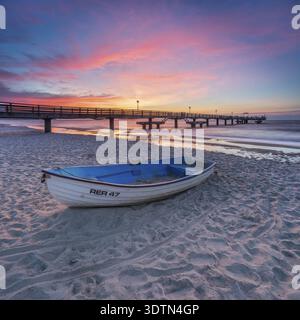 Pier am feinen Sandstrand der Ostsee bei Sonnenuntergang, Fischerboot am Strand, Ostseebad Rerik, Mecklenburg-Vorpommern, Deutschland Stockfoto