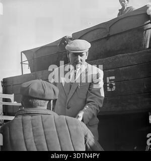 Ein Beamter oder Manager in formellem Anzug und flacher Mütze schüttelt einem Arbeiter vor einem Transportwagen auf der Fischfarm Donrybkombinat im Bezirk Slavjansk, 1970er Dieses authentische historische Schwarzweiß-Archivfoto fängt einen Moment des professionellen Respekts, der erfolgreichen Zusammenarbeit und der menschlichen Seite der sowjetischen Arbeitsbeziehungen im friedlichen Donbass vor dem Krieg ein und spiegelt die organisierte Natur der regionalen Aquakultur wider. Stockfoto