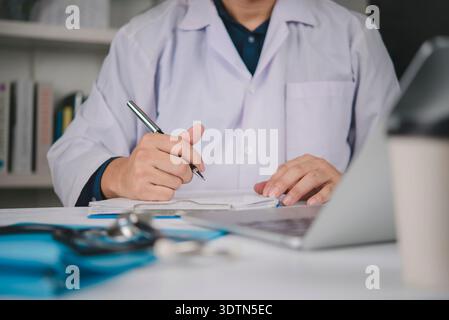 Doktor Handstift schreibt medizinisches Dokument auf Zwischenablage. Arztarbeitsplatz Laptop-Stethoskop. Gesundheitskonzept, Patientenbericht schreiben, Diagno Stockfoto