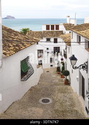 Treppen in einer schmalen Straße mit weiß getünchten Häusern und Blick über das Meer und den Felsen von Calpe in der Altstadt von Altea, Costa Blanca, Spanien Stockfoto