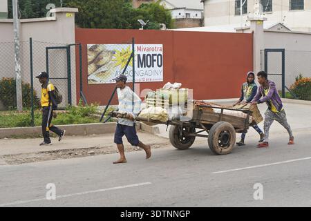 Antananarivo, Madagaskar - 24. April 2019: Unbekannter madagassischer Mann zieht Holzkarren mit Obst auf der Hauptstraße. Es gibt nicht viele Geschäfte in Madagaskar Stockfoto