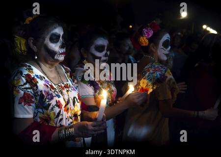 Merida, Cementerio General, Mexiko - 31. Oktober 2018: Drei customed Frau gekleidet wie Catrinas mit Totenkopf Make-up Probleme mit der Kerzen bet Stockfoto
