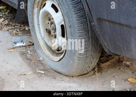 Close-up beschädigten Reifens. Das Rad der PKW-Reifen lecken. Reifenpanne warten auf die Reparatur. Verlassenes Auto auf dem Parkplatz. Stockfoto