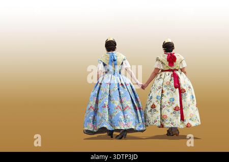 Rückansicht von zwei jungen spanischen Frauen in traditionellen Outfits vor orangefarbenem Hintergrund Stockfoto