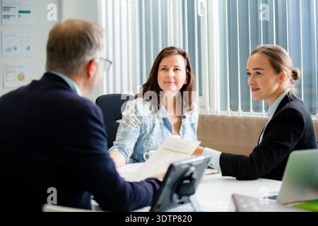 Erfahrene Führungskraft, die ein Geschäftstreffen leitet und zuhört, wie die Kollegin ein Dokument vorlegt. Echte Menschen, die zusammenarbeiten. Stockfoto