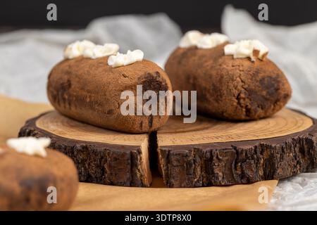 Ein schwarzer Kartoffelkuchen liegt auf einem Servierbrett und Papier, ein süßer Kuchen aus Butter und eine große Menge Kakao gemischt mit Biskuitkuchen und Cognac Stockfoto