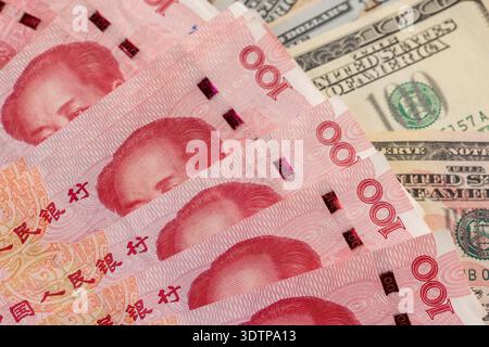 Rot-chinesisches Bargeld in Stückelungen von hundert Yuan und amerikanischen Dollar, ein Stapel Papiergeld von amerikanischem und chinesischem Geld Stockfoto