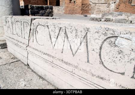Antike römische Steinmauer mit gemeißelter lateinischer Inschrift von archäologischer Stätte in Italien Stockfoto