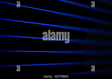 Blaue Strahlen gleiten durch dunkle Atmosphäre. Nachtlicht. Stockfoto