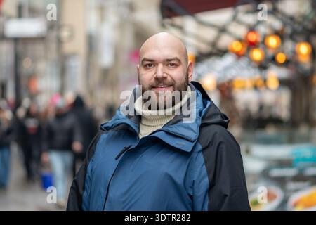 Erwachsener Mann in Winterkleidung, der im Winter in der Fußgängerzone der Stadt posiert Stockfoto