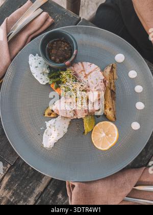 Gegrilltes Fischfilet mit Gemüse, Kräutern und Zitrusfrüchten auf eleganter Keramikplatte in Holbox, Mexiko. Stockfoto