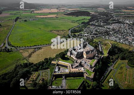 Hochwinkelperspektive einer massiven Steinfestung auf einem Felsvorsprung. Das historische Wahrzeichen überblickt ein weitläufiges grünes Tal, Straßen Stockfoto