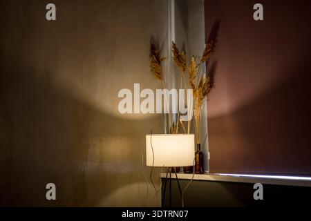 Eine stilvolle Innenraumszene mit sanfter Beleuchtung, dekorativen Pflanzenarrangements und eleganten Farbtönen, die das Ambiente eines modernen Wohnraums unterstreichen Stockfoto