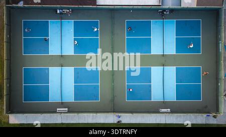 Aus der Vogelperspektive sehen Sie pulsierende blaue Pickleball-Plätze, die sich im Kontrast zum umgebenden Grün befinden und die Energie der Spieler in Bewegung, Coronado, Californ, einfangen Stockfoto