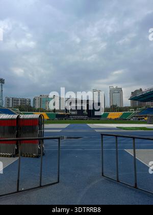 Ein fesselnder Blick auf ein leeres Stadion mit einem modernen Bildschirm unter einem bewölkten Himmel Stockfoto