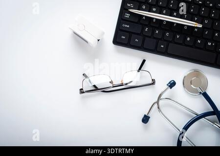 Ärzte Schreibtisch flach gelegt Hintergrund des Stethoskops Pulsoximeter Laptop Brille und Stift auf Tisch mit Kopierraum Stockfoto