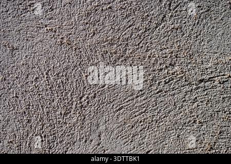Vollbild-Nahaufnahme einer rauen grauen Betonwandtextur mit feinen Putzdetails und seitlicher Beleuchtung. Stockfoto