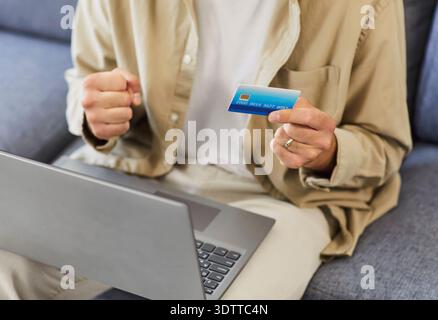 Nahaufnahme eines Mannes mit Kreditkarte und Laptop, der erfolgreiche Online-Zahlungen feiert Stockfoto