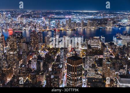 Nächtliches Panorama der Skyline von Manhattan mit beleuchteten Gebäuden und der Uferpromenade am East River in New York City, USA Stockfoto