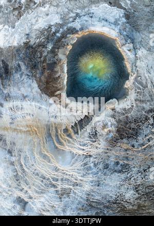 Aus der Vogelperspektive auf eine außerirdische geothermische Quelle, ihr türkisfarbenes Herz, umgeben von Mineralablagerungen und fadenförmigen Algen, entfaltet sich eine schroffe Schönheit, Reykja Stockfoto