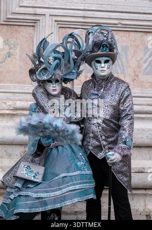 Fotogenes Paar in aufwendigen handgefertigten Kostümen posiert für die Kamera vor der Kirche San Zaccaria während des jährlichen Karnevals in Venedig, Italien. Stockfoto