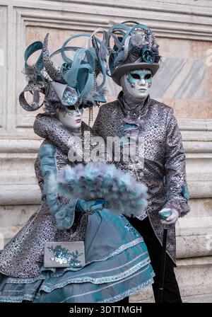 Fotogenes Paar in aufwendigen handgefertigten Kostümen posiert für die Kamera vor der Kirche San Zaccaria während des jährlichen Karnevals in Venedig, Italien. Stockfoto