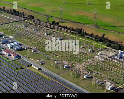 Luftaufnahme eines Industriegebiets mit Stromleitungen und Solarpaneelen im Kontrast zu den grünen Feldern, Civitavecchia, Latium, Italien. Stockfoto